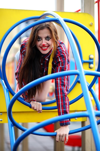 Jolie fille dans un maquillage de clown sur fond de foire et d'étapes