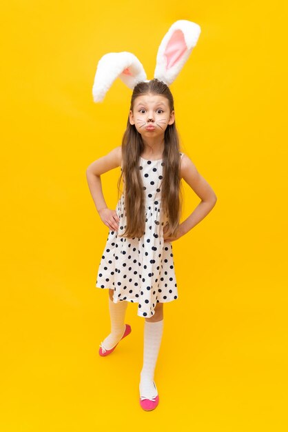 Jolie fille dans les oreilles de lapin de Pâques fantaisie et moustache peinte sur un fond isolé jaune Vacances de printemps de Pâques Une fille dans les oreilles d'un lapin de Pâques