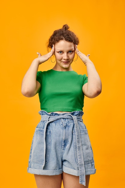 Jolie fille dans un t-shirt vert gestes avec les mains émotions fond jaune