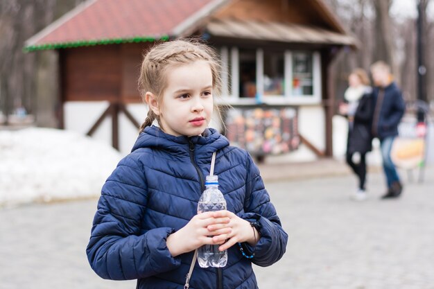 Jolie fille dans des verres boit de l'eau d'une bouteille achetée dans un camion de nourriture