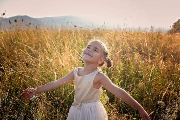 Jolie fille dansant dans une belle prairie avec du blé et des fleurs dans les montagnes