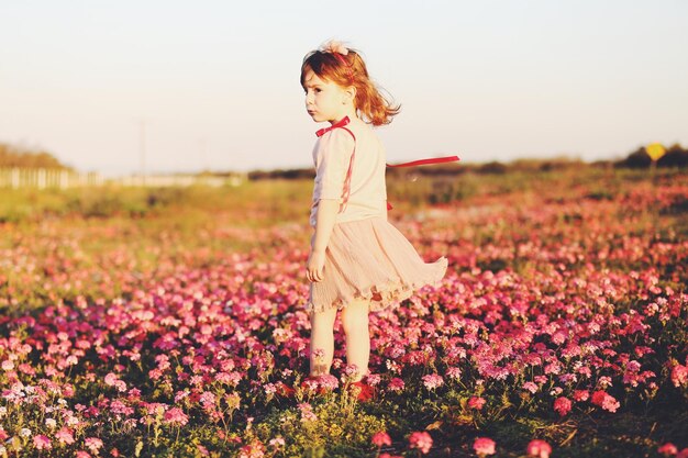 Photo une jolie fille debout au milieu des fleurs roses sur la terre