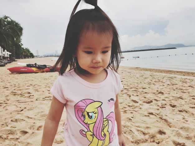 Une jolie fille debout sur la plage contre le ciel