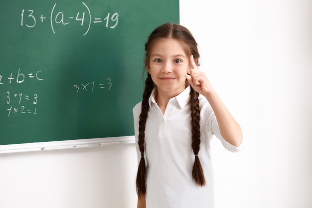 Jolie fille debout près du tableau en classe