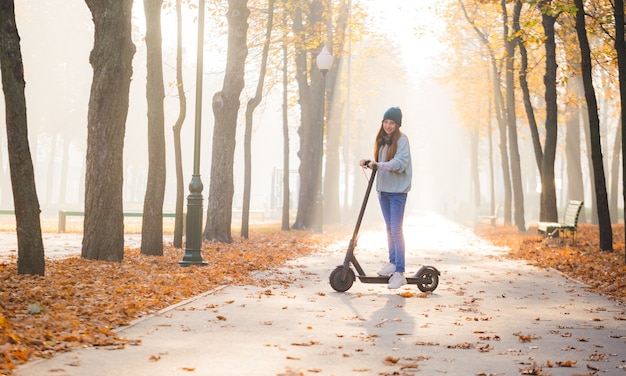 Jolie fille debout sur scooter dans la brume