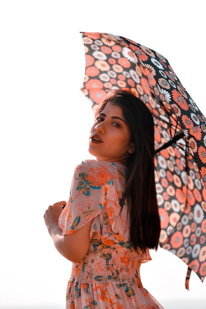 jolie fille décontractée avant pose tenant un parapluie sur la plage modèle pakistanais indien