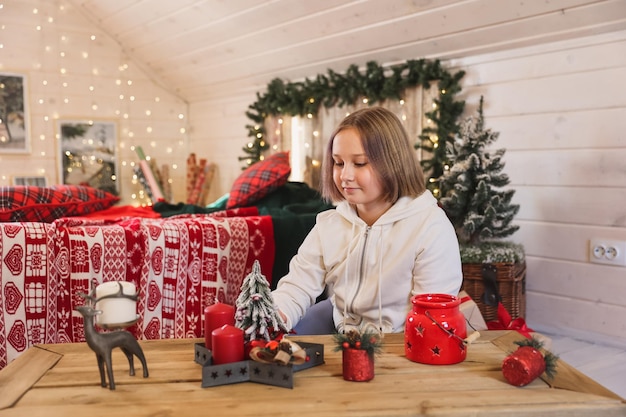 Jolie fille décore un arbre de Noël. Joyeuses fêtes de Noël et du nouvel an.