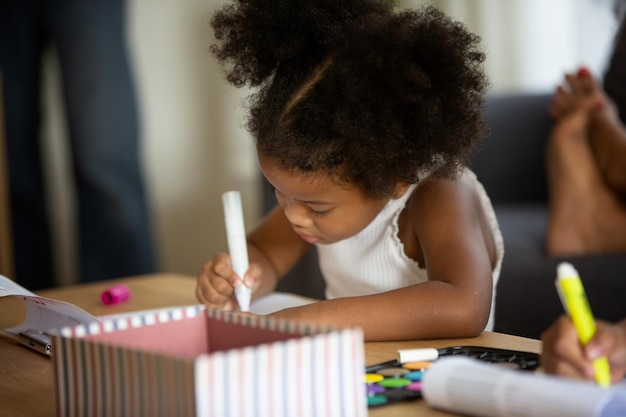 Photo une jolie fille dessine assise à table.