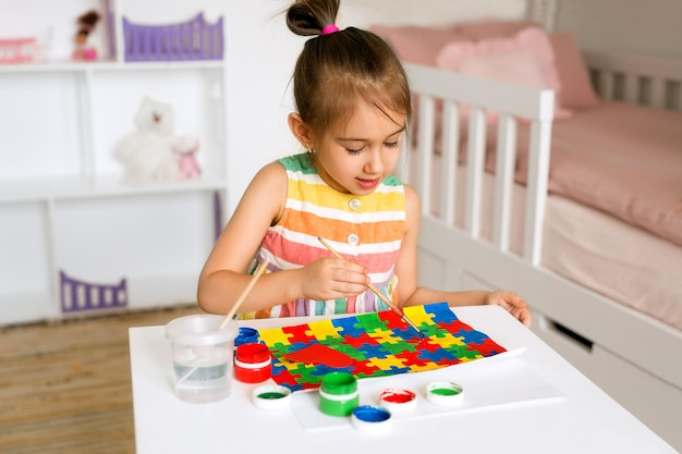 Jolie fille dessine un dessin dans la chambre des enfants à table pour la Journée mondiale de sensibilisation à l'autisme