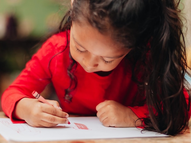 Une jolie fille dessine à la maison.