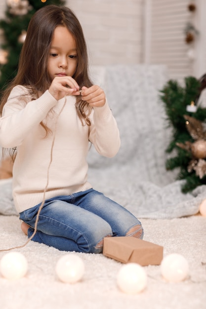 Jolie fille emballant des cadeaux de Noël à la maison