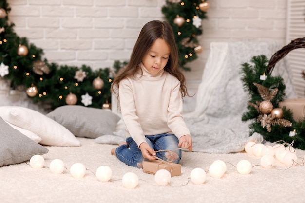 Jolie fille emballant des cadeaux de Noël à la maison