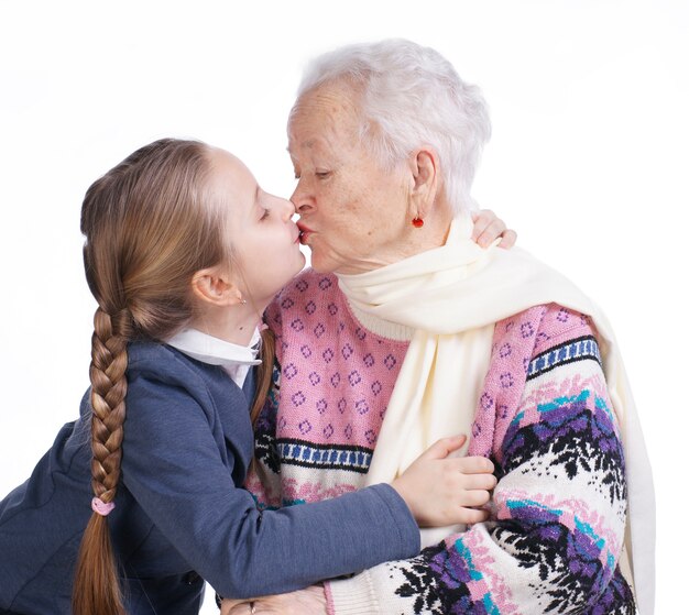 Jolie fille embrassant sa grand-mère sur fond blanc