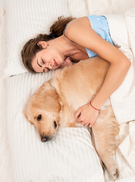 Jolie fille embrasse son propre chien retriever dans la chambre à l'intérieur