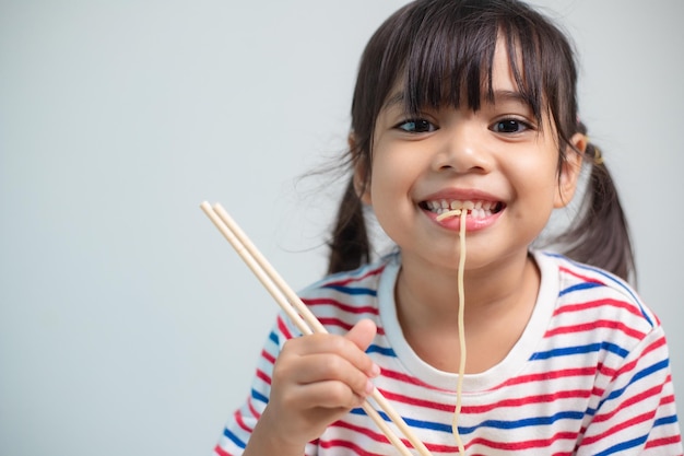 Jolie fille enfant asiatique mangeant de délicieuses nouilles instantanées à la maison