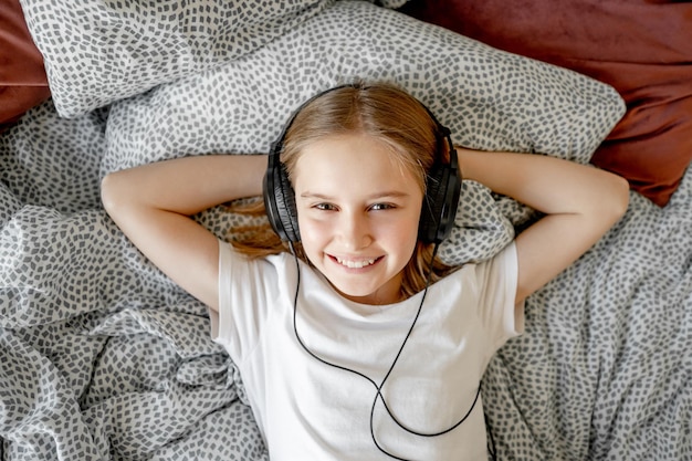 Jolie fille enfant dans les écouteurs au lit