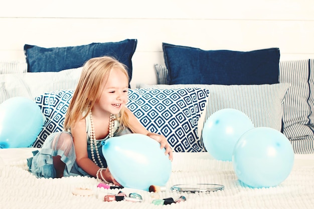 Jolie fille enfant s'amusant avec des ballons bleus à la maison. Petite fille, 2 ans