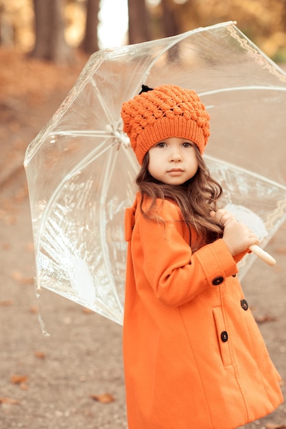 Jolie fille enfant tenant un parapluie à l'extérieur Porter un manteau et un chapeau élégants Marcher dans le parc