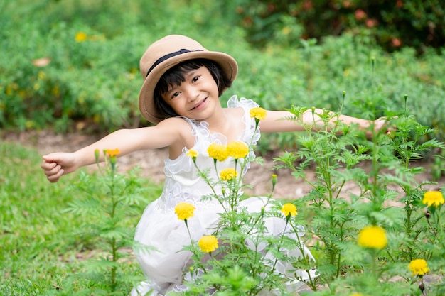 Jolie fille enfants rafraîchissent sur le jardin de fleurs dans le parc