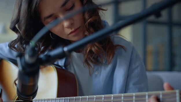 Photo jolie fille enregistrant le son de la guitare avec un microphone à condensateur musicienne exécutant une composition musicale dans un instrument à cordes jeune femme jouant des accords à la guitare dans un studio d'enregistrement à domicile