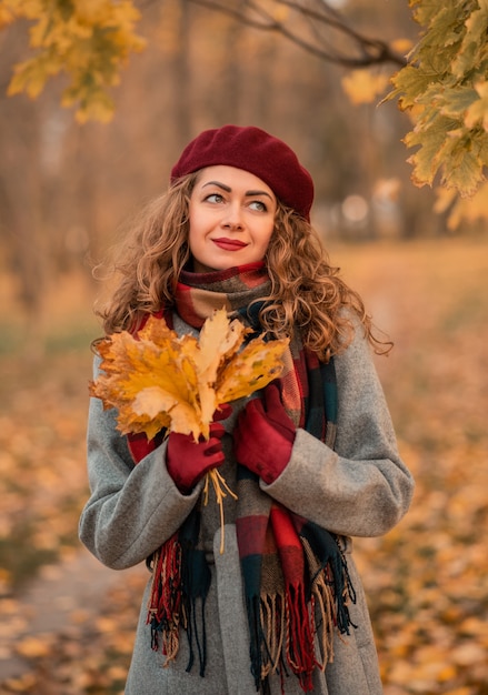 Jolie fille est vêtue d'un manteau gris, un béret rouge, des gants, enveloppés dans une écharpe à carreaux.