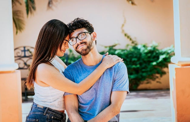 Jolie fille étreignant tendrement son petit ami à l'extérieur Fille étreignant son petit ami pendant qu'il lui sourit Heureux couple Fille étreignant son petit ami à l'extérieur