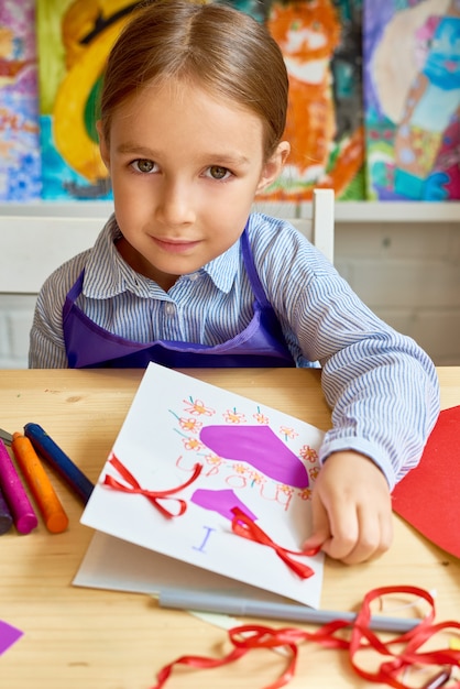 Jolie fille faisant une carte à la main pour maman