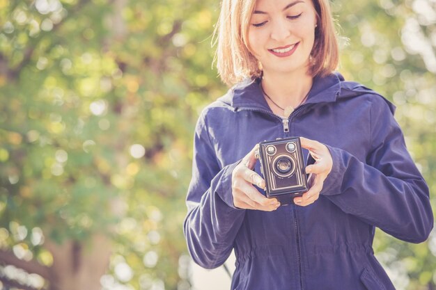 Jolie fille fait des photos avec un appareil photo vintage à l'extérieur