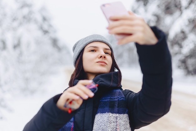 Une jolie fille fait un selfie au milieu d&#39;une route forestière enneigée