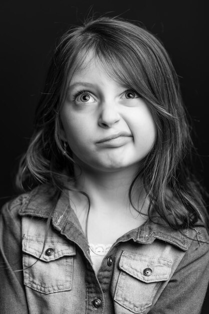 Photo une jolie fille fait un visage en détournant le regard sur un fond noir.