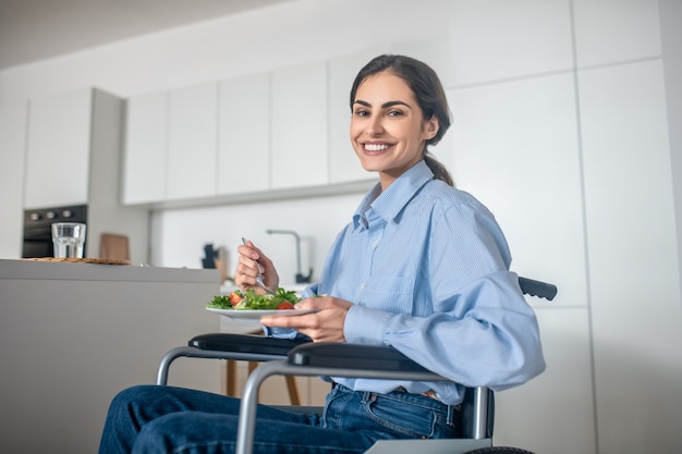 Une jolie fille sur un fauteuil roulant dans la cuisine à la maison