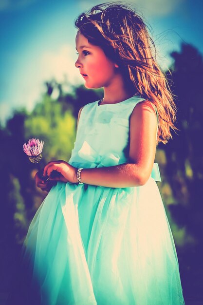 Photo une jolie fille avec une fleur de chardon qui détourne le regard en dehors.