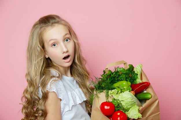 Jolie fille sur fond rose avec des légumes