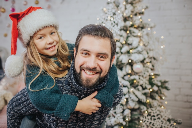 Jolie fille heureuse jouant avec papa à la maison dans l'atmosphère de Noël