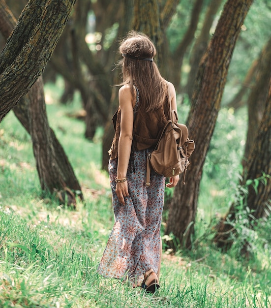 Jolie fille hippie marchant parmi les arbres de la forêt. le concept d'unité avec la nature