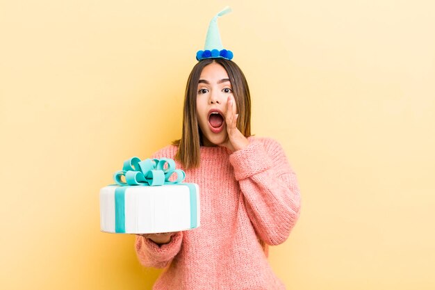 Jolie fille hispanique se sentant heureuse en donnant un grand cri avec les mains à côté du concept d'anniversaire de la bouche