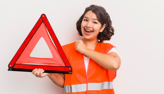 Jolie fille hispanique se sentant heureuse et faisant face à un défi ou célébrant un triangle d'accident de voiture