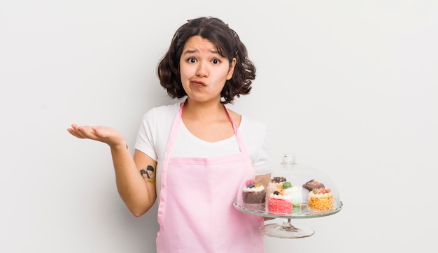 Jolie fille hispanique se sentant perplexe et confuse et doutant du concept de gâteaux faits maison