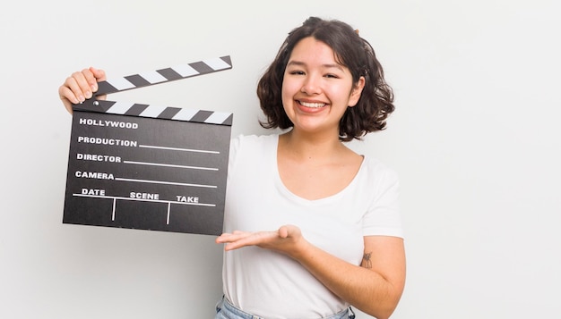 Jolie fille hispanique souriant joyeusement se sentant heureuse et montrant un concept concept de cinéma