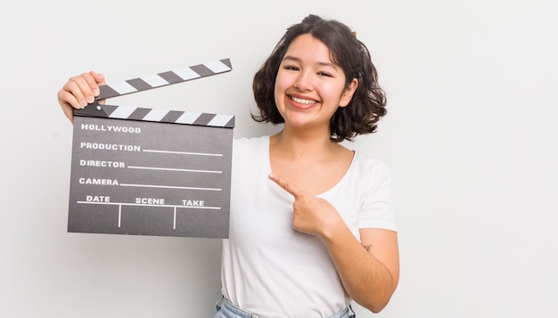 Jolie fille hispanique souriant joyeusement se sentant heureuse et pointant vers le concept de cinéma latéral