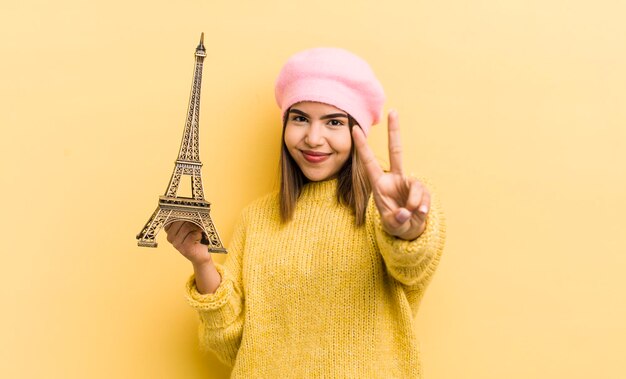 Jolie fille hispanique souriante et regardant heureuse gesticulant concept de victoire ou de paix paris