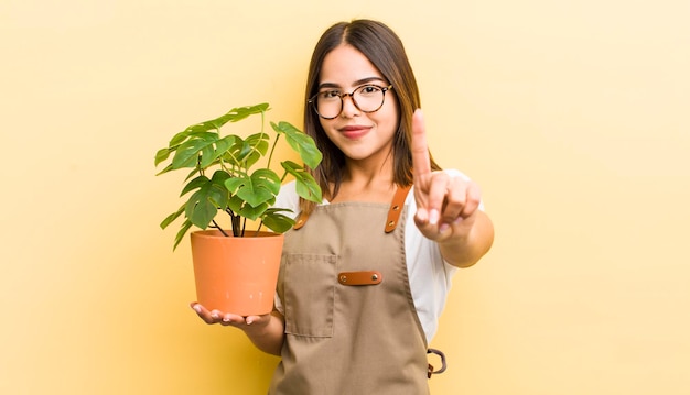 Jolie fille hispanique souriante et sympathique montrant le concept de plante numéro un