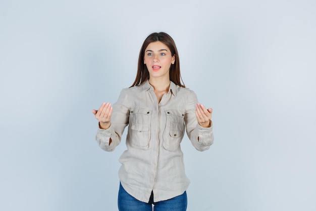 Jolie fille invitant à venir, détournant les yeux en chemise et se demandant.