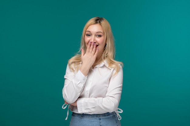 Jolie fille jeune jolie fille blonde dans une chemise blanche riant de quelque chose et couvrant la bouche