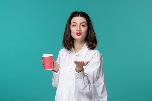 Jolie fille jolie brune jeune fille douce en chemise blanche envoyant des baisers avec une tasse de café rose