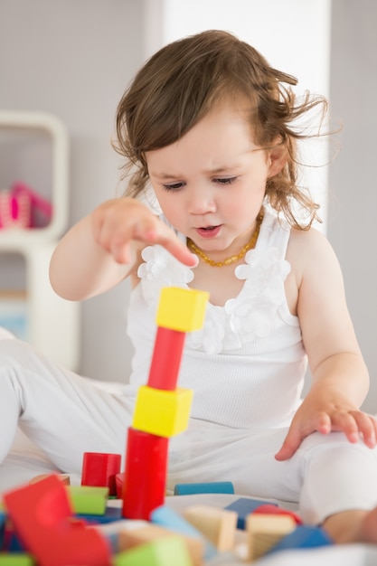 Jolie fille jouant avec des blocs de construction sur le lit