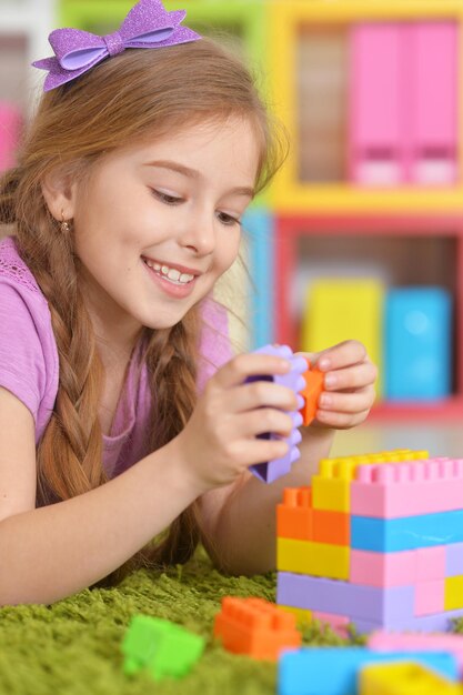 Jolie fille jouant avec des blocs de plastique colorés dans la chambre