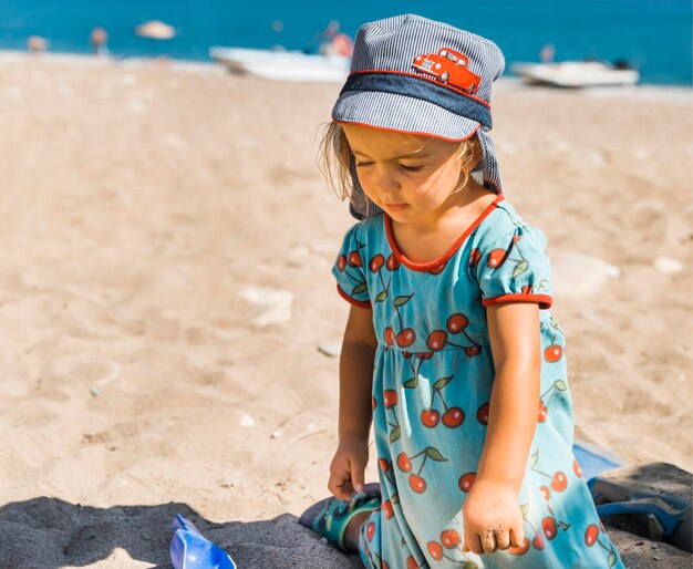 Photo une jolie fille jouant dans le sable sur la plage.