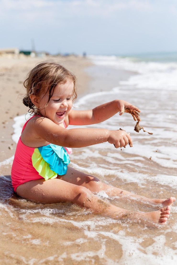 Photo une jolie fille jouant sur le sable de la plage.