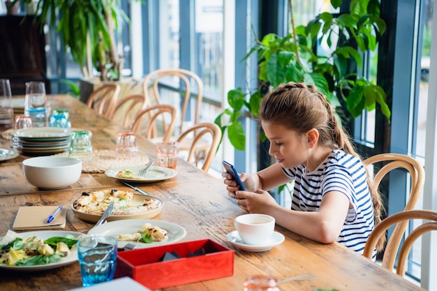 Une jolie fille jouant sur son smartphone dans la cuisine